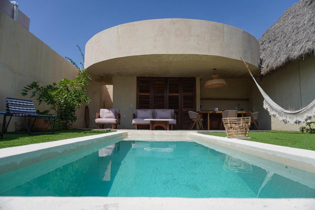 een zwembad voor een huis met een rieten dak bij Villa Yahualli in #N/A