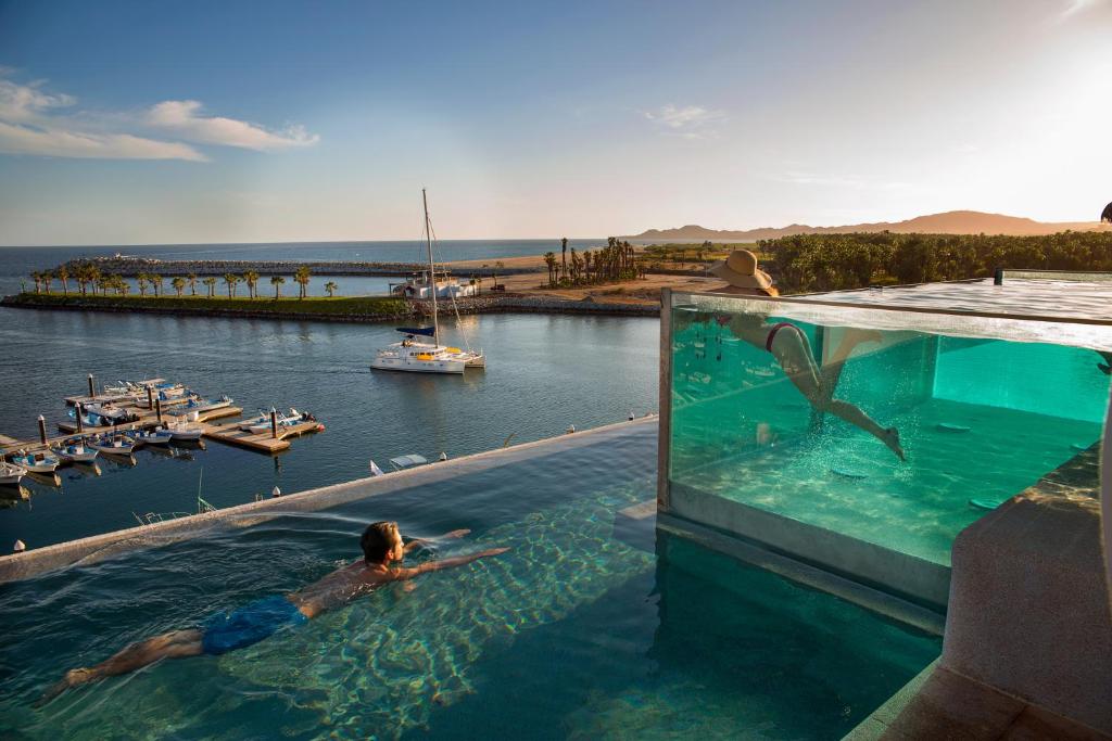 a man in a swimming pool with a shark in the water at Hotel El Ganzo Adults Only in San José del Cabo