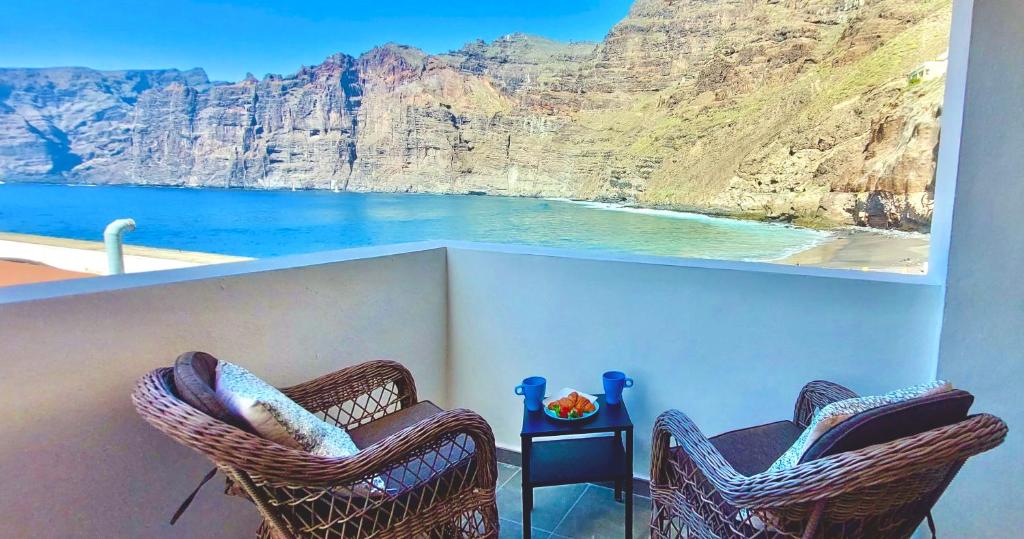 two chairs on a balcony with a view of the ocean at National Trust Beach Apartment in Santiago del Teide