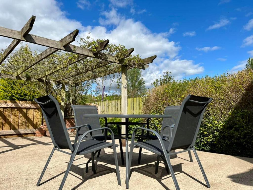 a patio with a table and chairs under a pergola at Bluebell Cottage in Ross on Wye