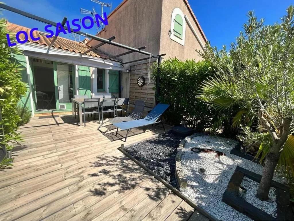 une terrasse en bois avec une table et des chaises. dans l'établissement Pavillon Piscine Parking Privé, à Valras-Plage