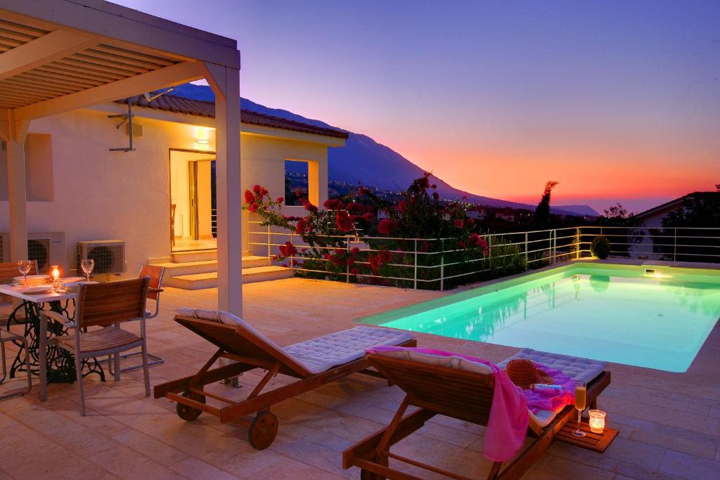 ein Haus mit einem Pool mit einem Tisch und Stühlen in der Unterkunft Villa Litorina Ideales Resort in Kefalonia