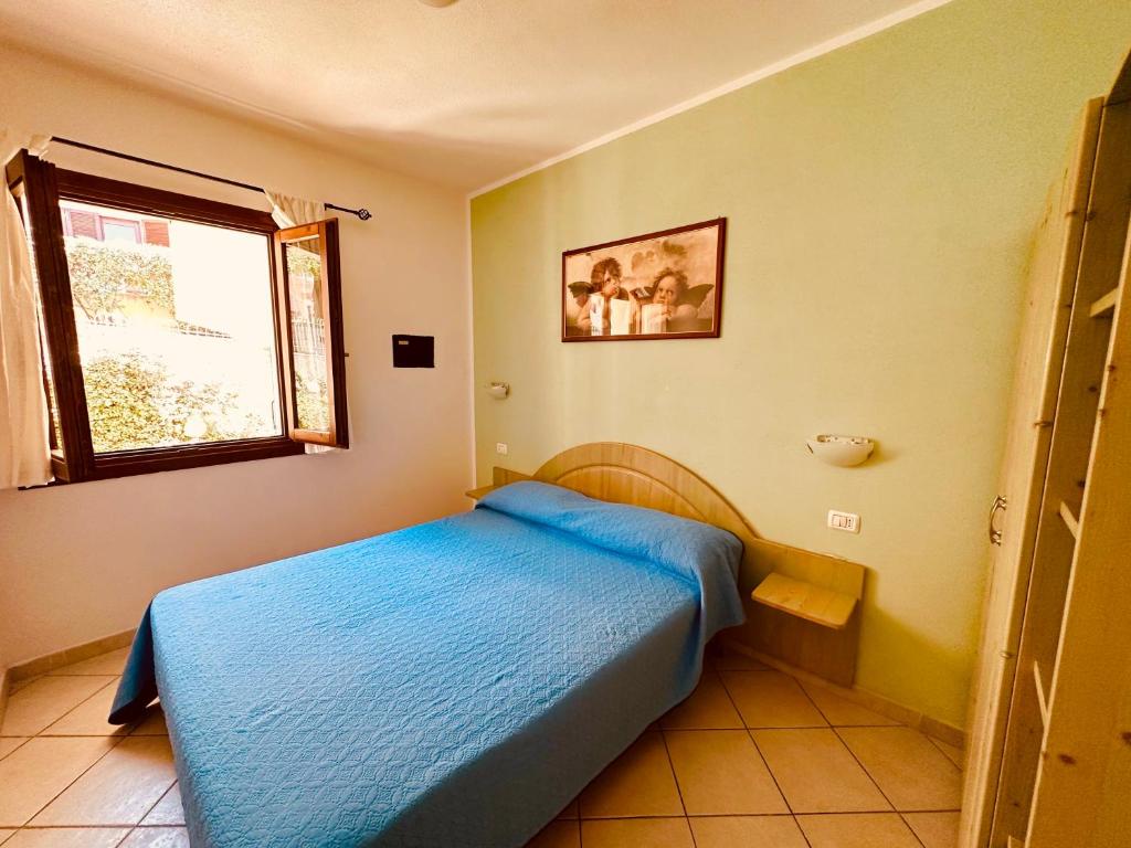 um quarto com uma cama azul e uma janela em Borgo Turchese Residence em Badesi