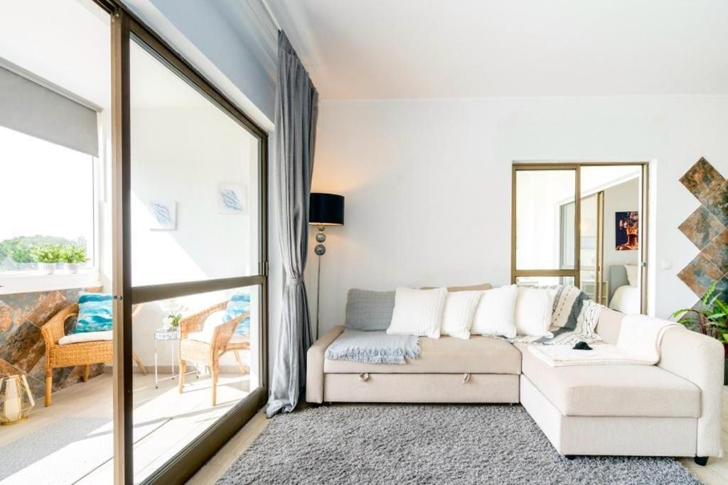 sala de estar con sofá blanco y ventana grande en Spacious 1 bed in Vilamoura, Fast Wifi & Pool, en Quarteira