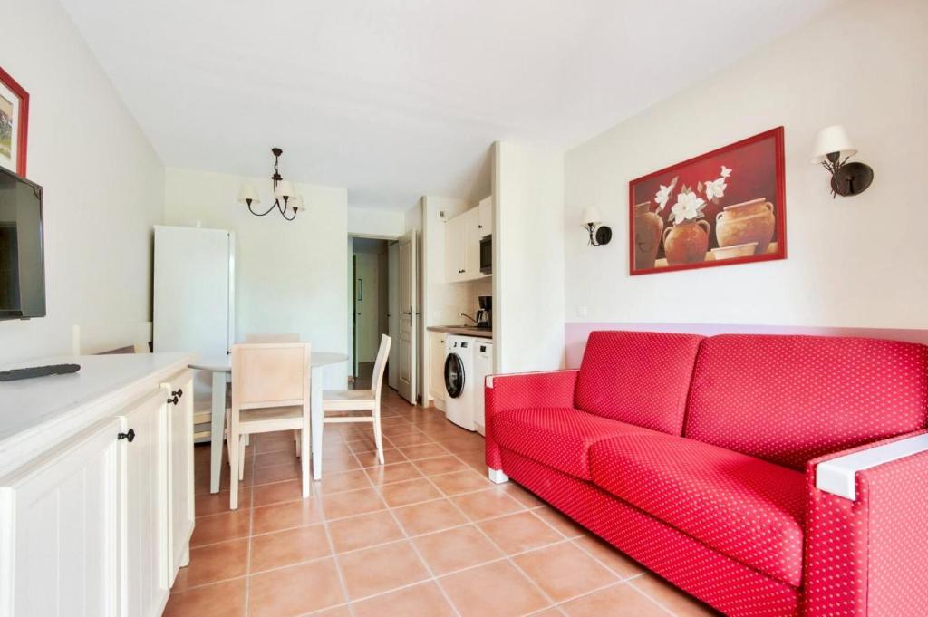 un salon avec un canapé rouge et une cuisine dans l'établissement Village Pont Royal en Provence - maeva Home - Appartement 2 pièces 4 personnes - Confort MAE-7164, à Mallemort