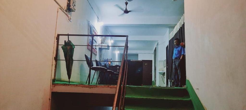 einen Flur mit Treppen und ein Mann in einem Zimmer in der Unterkunft OYO National Inn in Jamshedpur