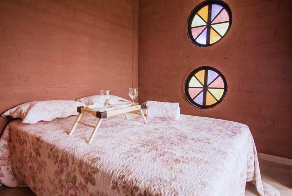 een slaapkamer met een bed met een tafel en 2 ramen bij Daya Ma Hospedagem in Alto Paraíso de Goiás