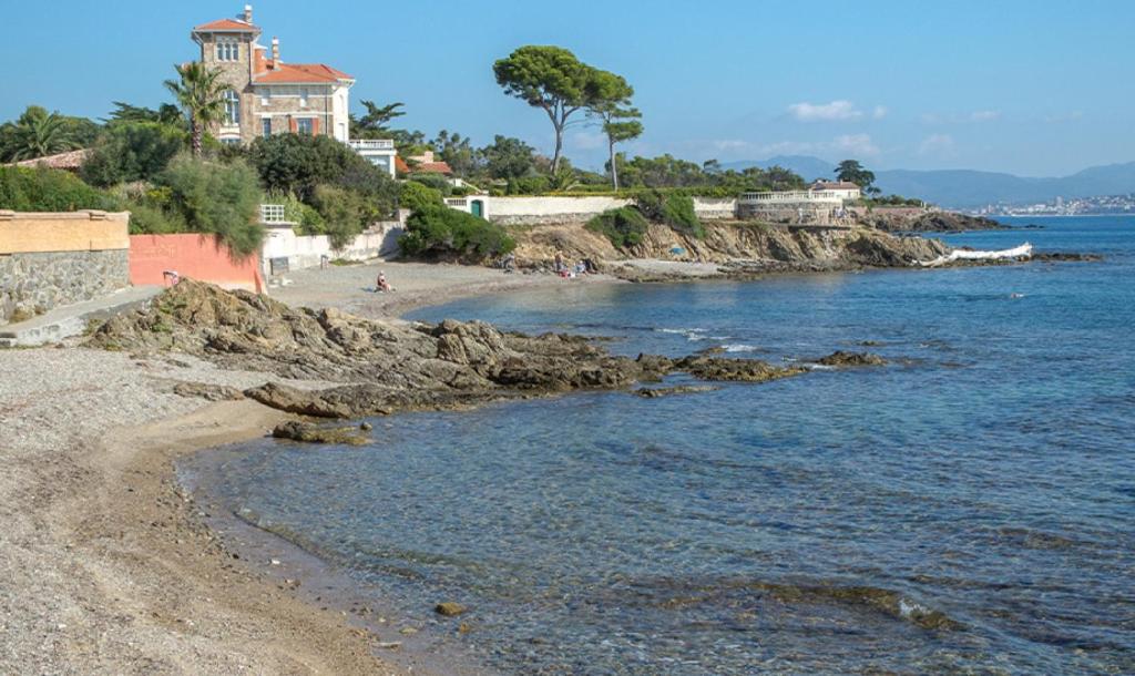 une plage avec une maison sur une colline à côté de l'eau dans l'établissement Balcon sur la Méditerranée St Aygulf centre, 4 couchages, à Fréjus