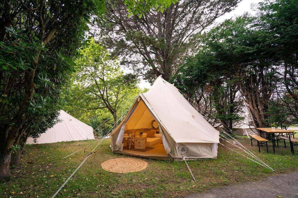 2 tentes dans un champ avec une table et des arbres dans l'établissement Kampaoh Playa Troenzo, à Celorio