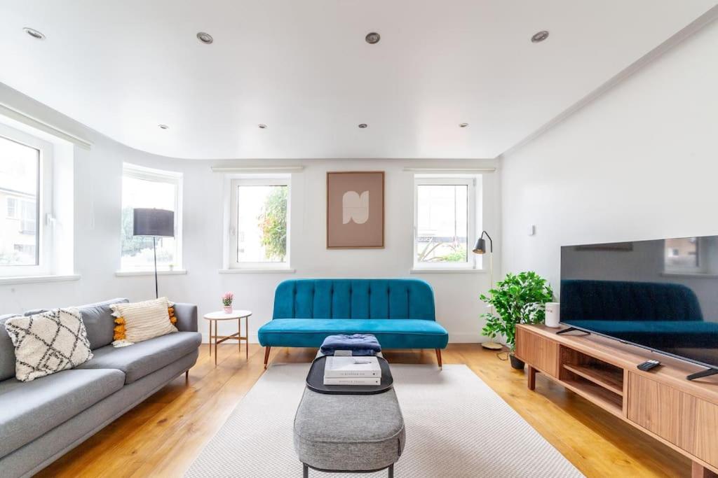 a living room with two blue couches and a tv at Stylish 3-bed near Camden Town & King's Cross in London
