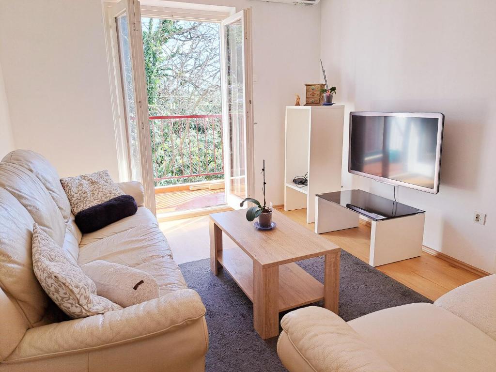 a living room with a couch and a tv at Apartment Tree House in Lovran