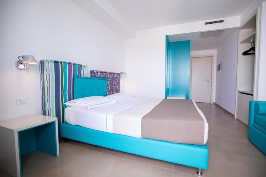 a bedroom with a blue and white bed and a table at Hotel Cicò in Torre Santa Sabina