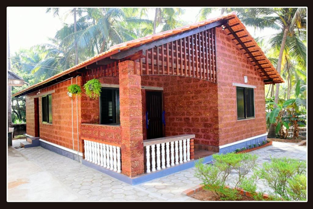 a small red brick house with a porch at Tiny Waves in Udupi