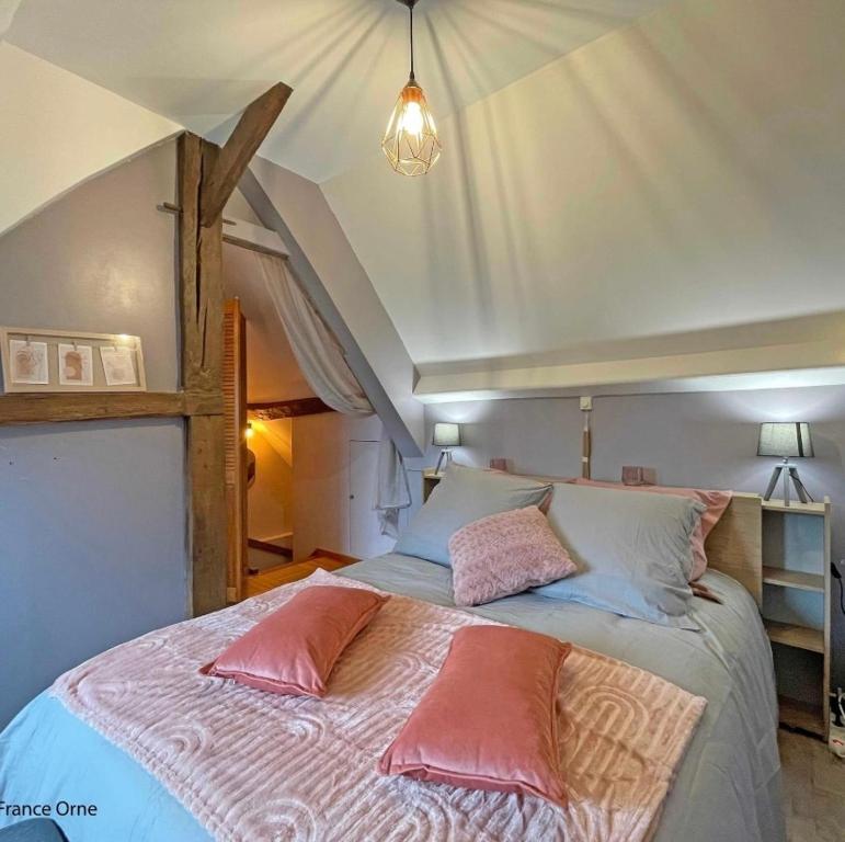 Un dormitorio con una cama con almohadas rosas. en Le p’tit Suisse Normand en Putanges