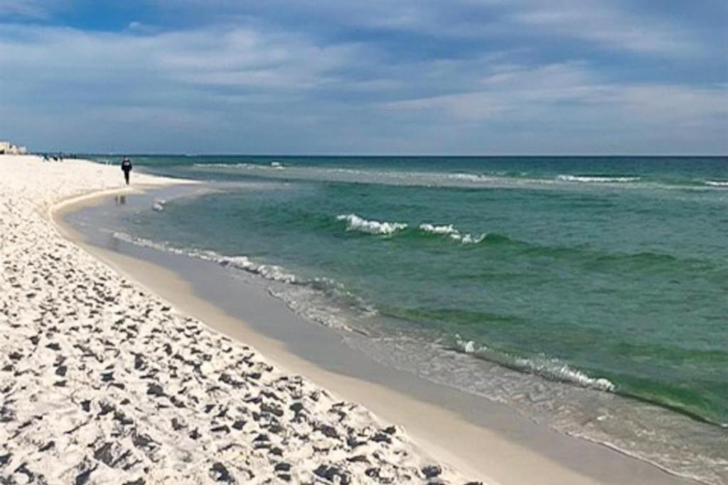 una persona caminando por una playa con el océano en Cottages of Crystal Beach Sea La Vie, en Destin