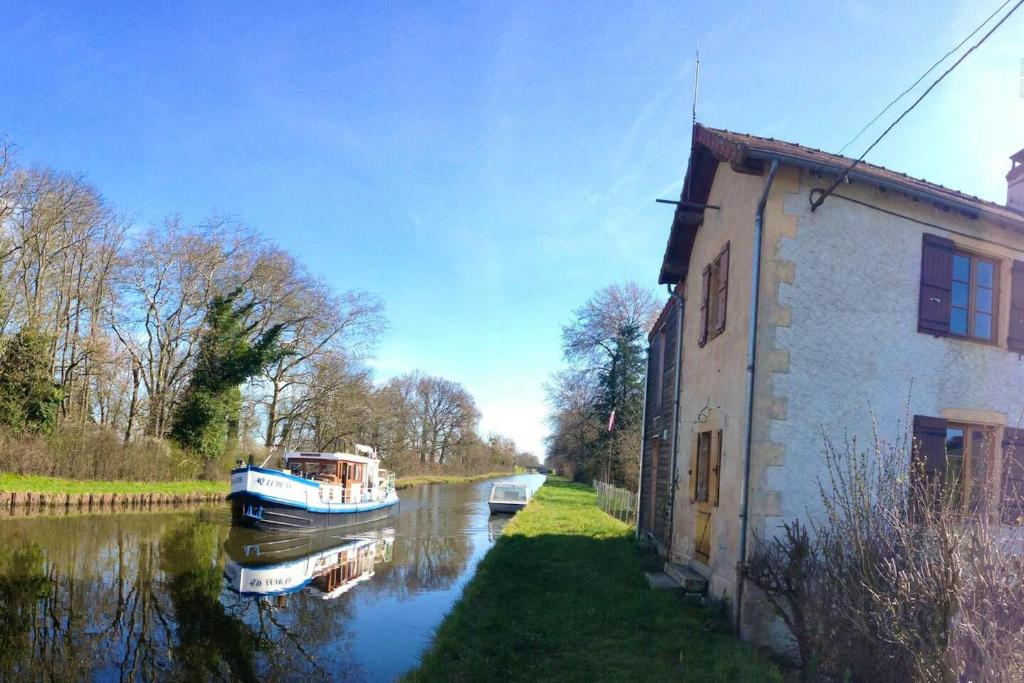 ein Boot auf einem Fluss neben einem Gebäude in der Unterkunft Appartement d'une chambre avec wifi a Bourg le Comte in Bourg-le-Comte