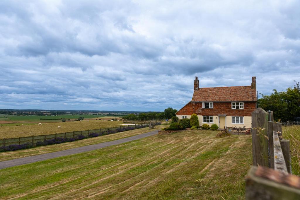 a house on the side of a field next to a road at Coldharbour Cottage in Stone