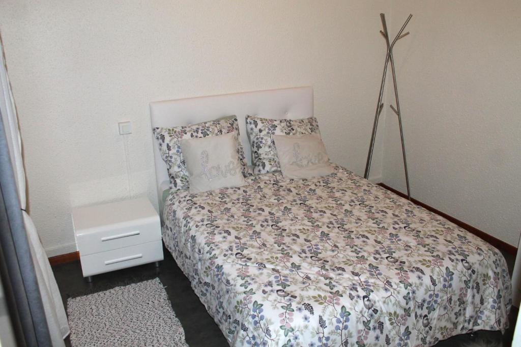 sypialnia z łóżkiem z poduszkami i stolikiem nocnym w obiekcie Appartement au calme. w mieście Thaon-les-Vosges