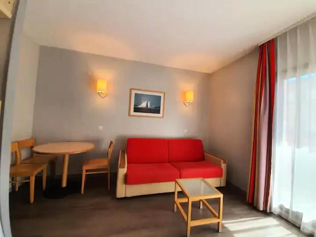un salon avec un canapé rouge et une table dans l'établissement Résidence Centre - maeva Home - Studio 4 personnes - Sélection MAE-9024, à La Rochelle