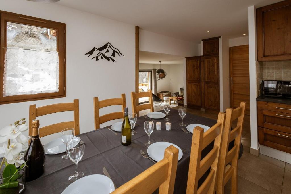 uma sala de jantar com uma mesa com garrafas de vinho e copos em Chalet Lova em Valloire