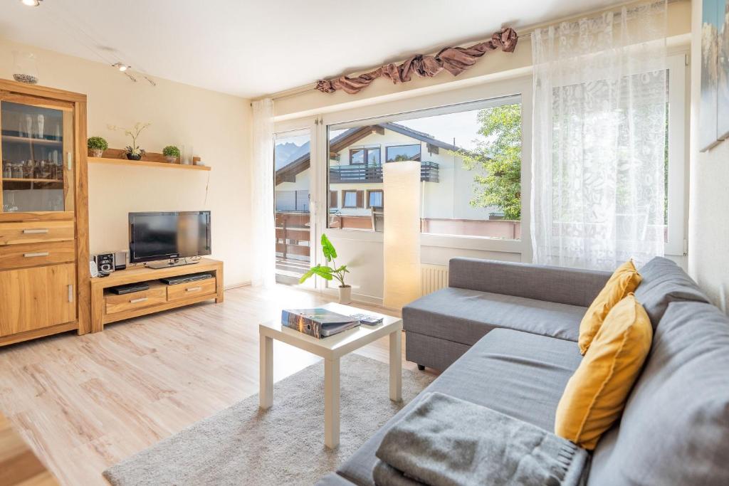 ein Wohnzimmer mit einem Sofa und einem TV in der Unterkunft Sonnenkopfblick in Obermaiselstein