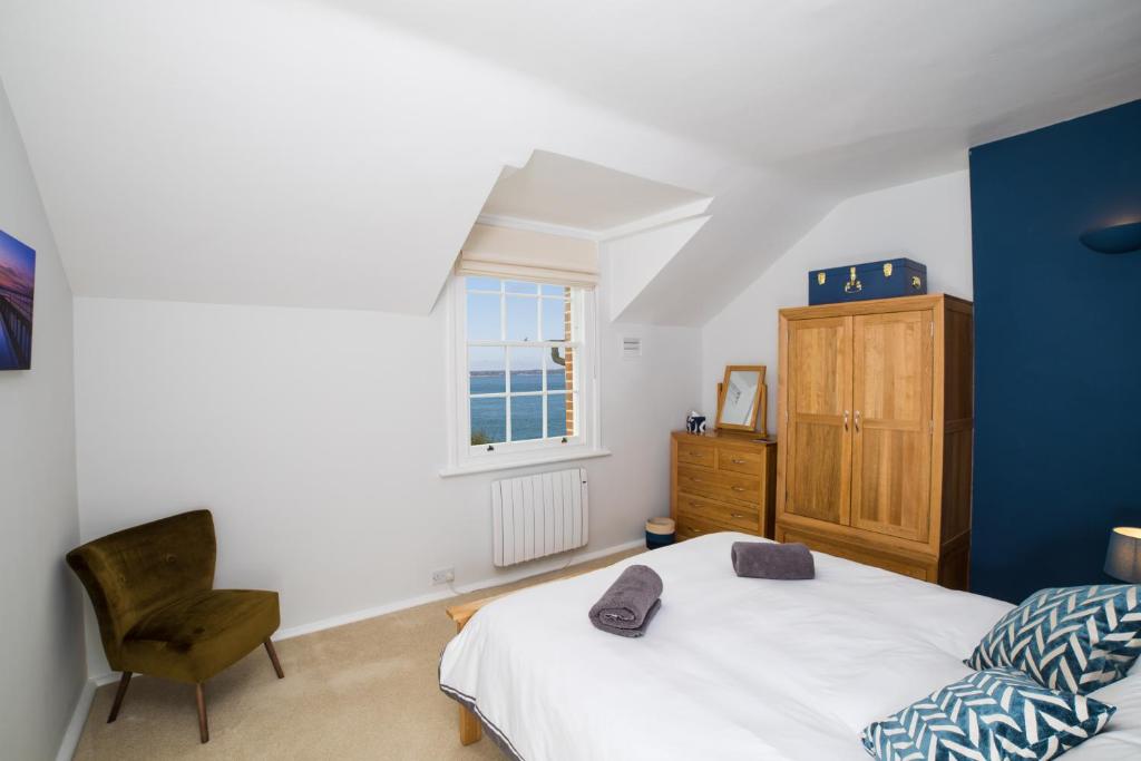 a bedroom with a bed and a chair and a window at Fantastic sea views and amazing coastal scenery in Yarmouth