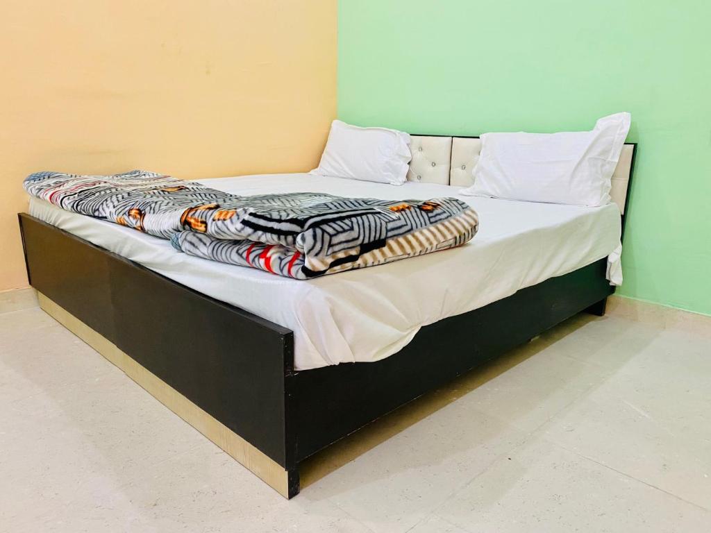 a bed with a black frame and white sheets and pillows at OYO Friends Hotel in Rewāri