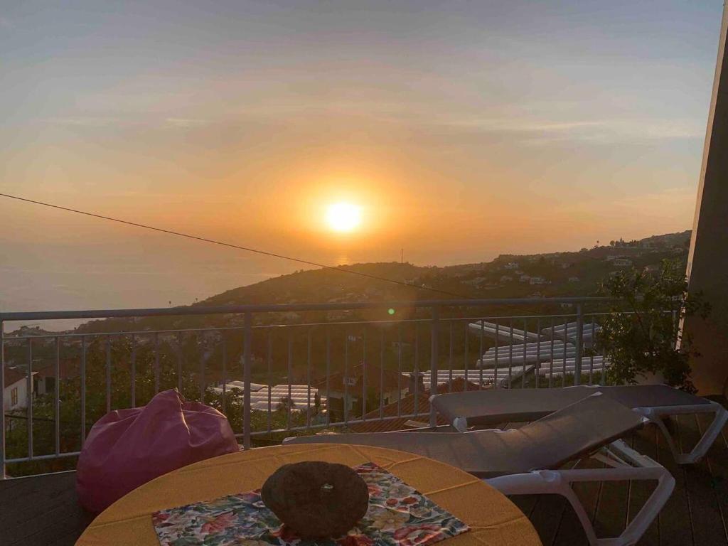 - un balcon avec une table et des chaises pour admirer le coucher du soleil dans l'établissement One bedroom house with wifi at Ponta do Sol, à Ponta do Sol