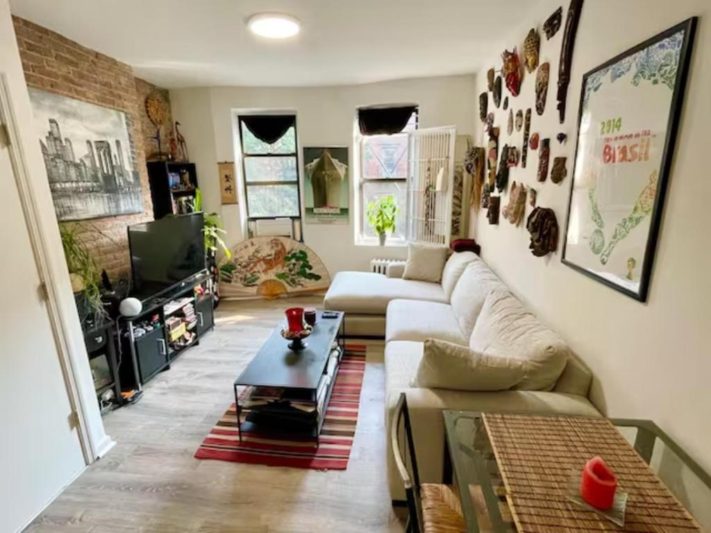 Charming One-Bedroom Apartment in South Chelsea في نيويورك: غرفة معيشة مع أريكة وطاولة قهوة