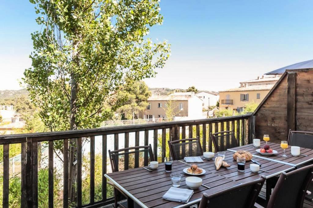 a table on a balcony with a view of a city at Les Coteaux de Pont Royal en Provence - maeva Home - Appartement 3 pièces 6 214 in Mallemort