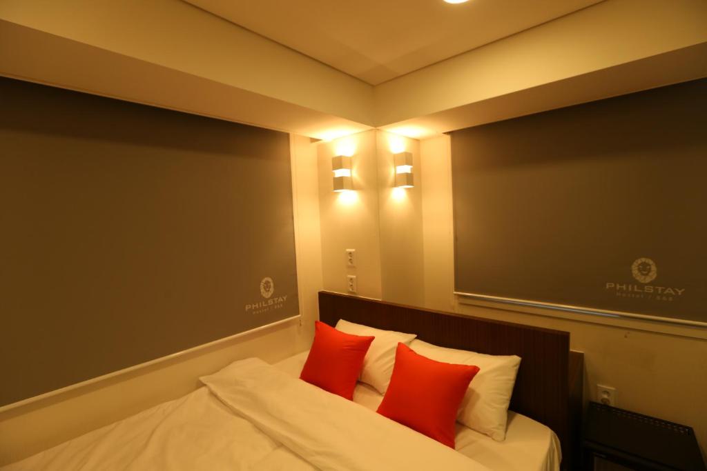 a bedroom with a bed with two red pillows at Philstay Dongdaemun Economic in Seoul