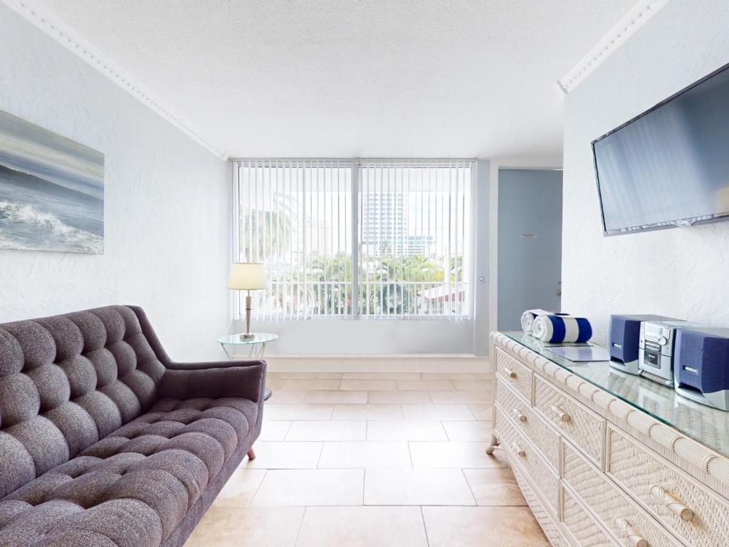 a living room with a couch and a flat screen tv at The Grand Resort and Spa & Worthington All Male in Fort Lauderdale
