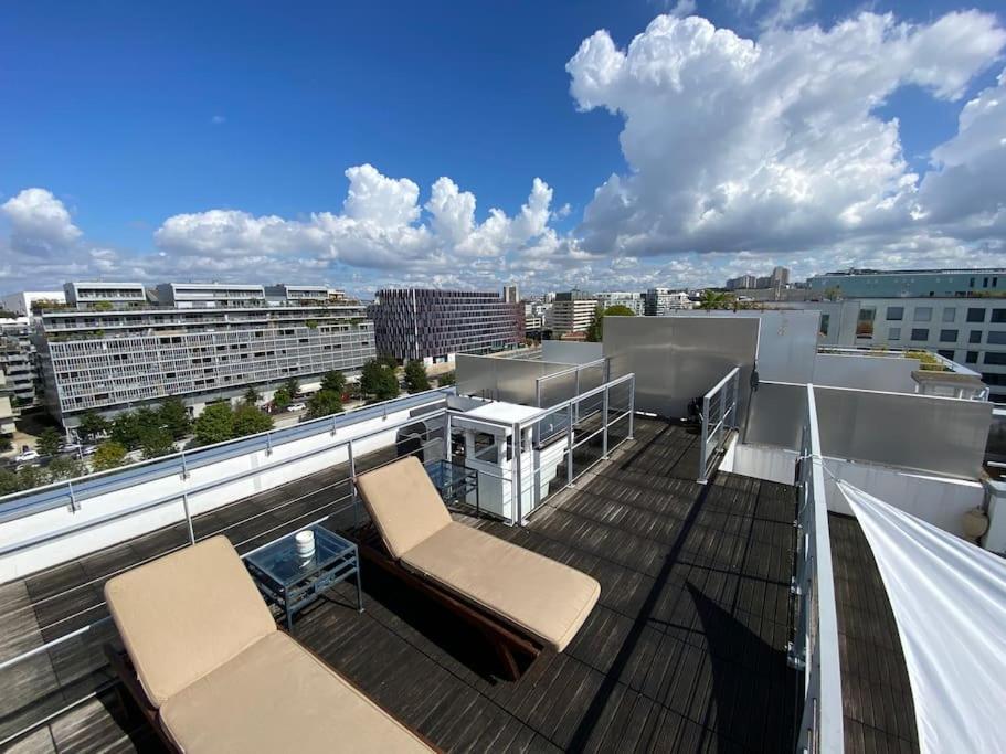 un balcon avec deux chaises et une vue sur une ville dans l'établissement Penthouse Luxueux avec Terrasse Panoramique, à Boulogne-Billancourt