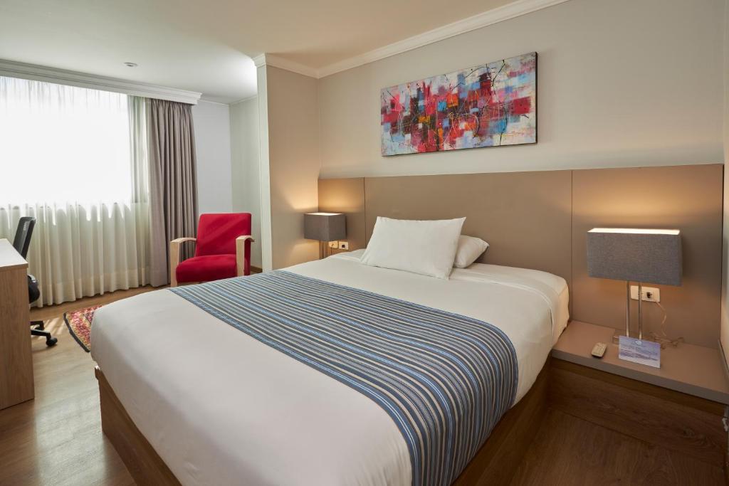 Habitación de hotel con cama y silla roja en Hotel Saint Simon, en Bogotá