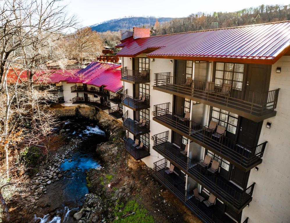 Bear Creek Inn Gatlinburg, TN في غاتلينبرغ: اطلالة جوية على مبنى فيه بلكونات ونهر