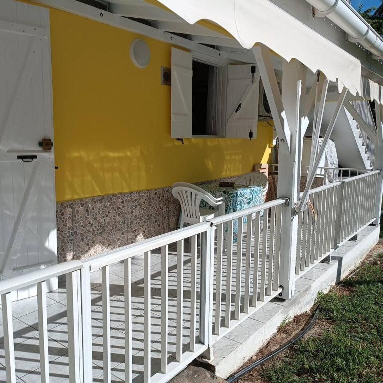 a porch of a yellow house with a white railing at Maison charmante au cœur de Le Gosier avec cheminée in Le Gosier