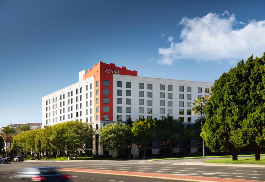 un bâtiment situé dans une rue où une voiture passe dans l'établissement Hotel Zessa Santa Ana, a DoubleTree by Hilton, à Santa Ana