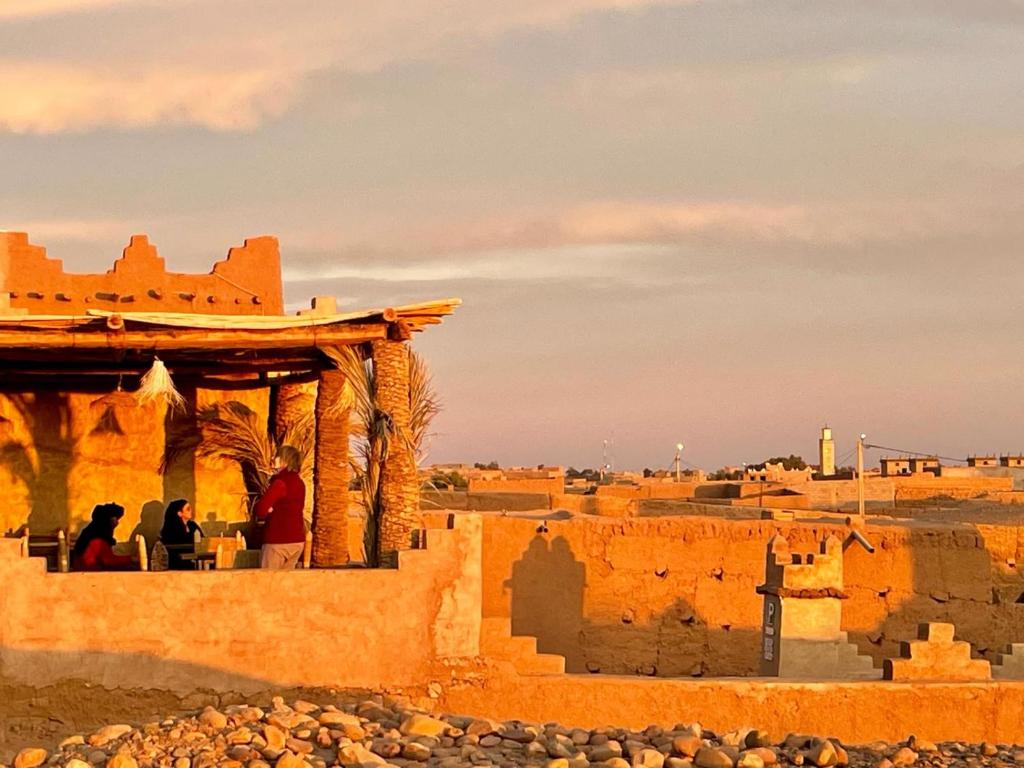 姆哈米德Auberge Kasbah Dar Sahara Tours的两人坐在沙漠中一座建筑的阳台上