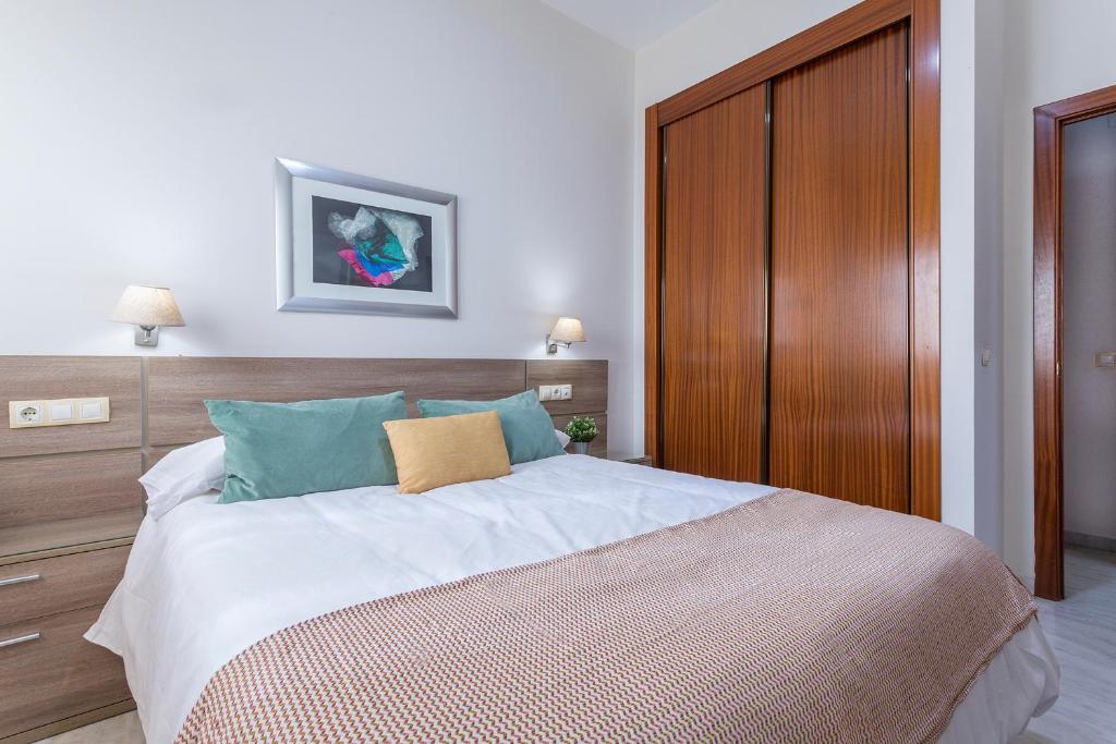 een slaapkamer met een groot bed met een houten hoofdeinde bij LuxSevilla Moderno 1 Room Piscina Parking in Bormujos