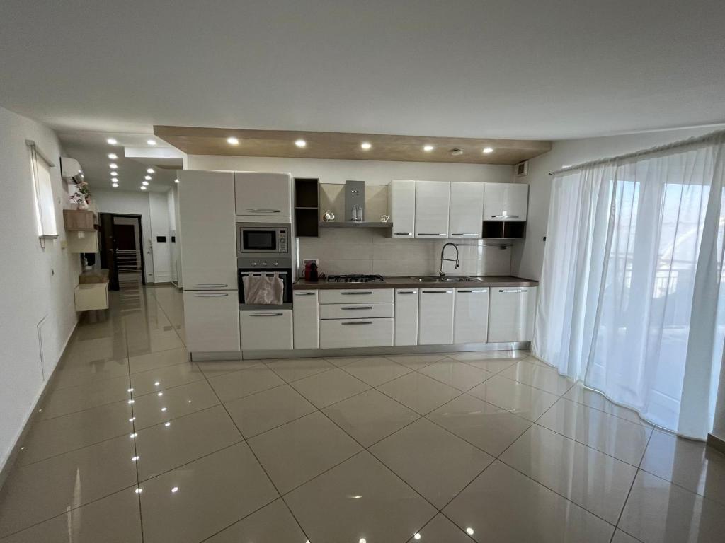 una cucina con armadietti bianchi e pavimento piastrellato di Casa vacanza Helios a Leonforte