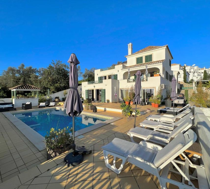 a villa with a swimming pool with lounge chairs and an umbrella at Tavira Terrace in Tavira