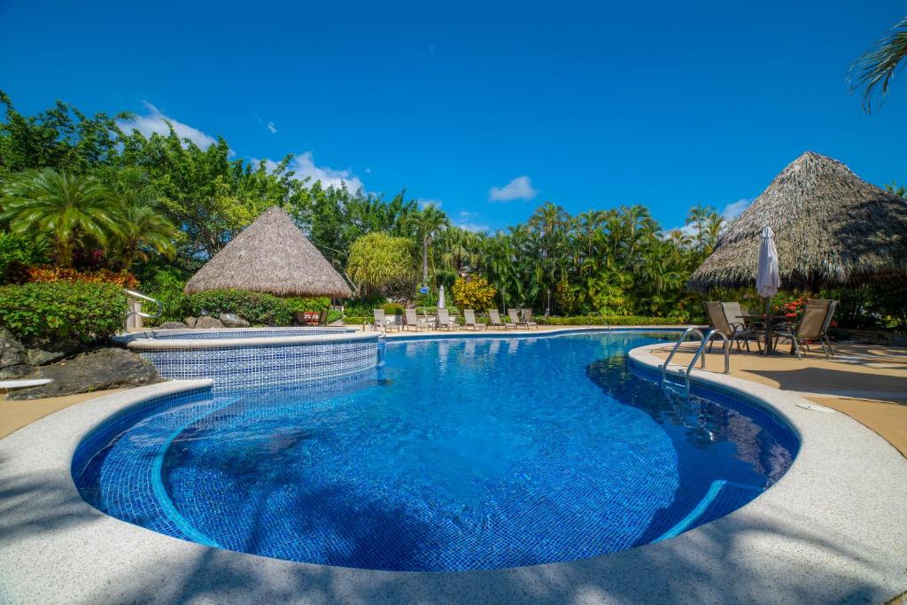 einen Pool in einem Resort mit Stühlen und Sonnenschirmen in der Unterkunft Los Suenos Resort Colina 8F - 2 bdr by Stay in CR in Herradura