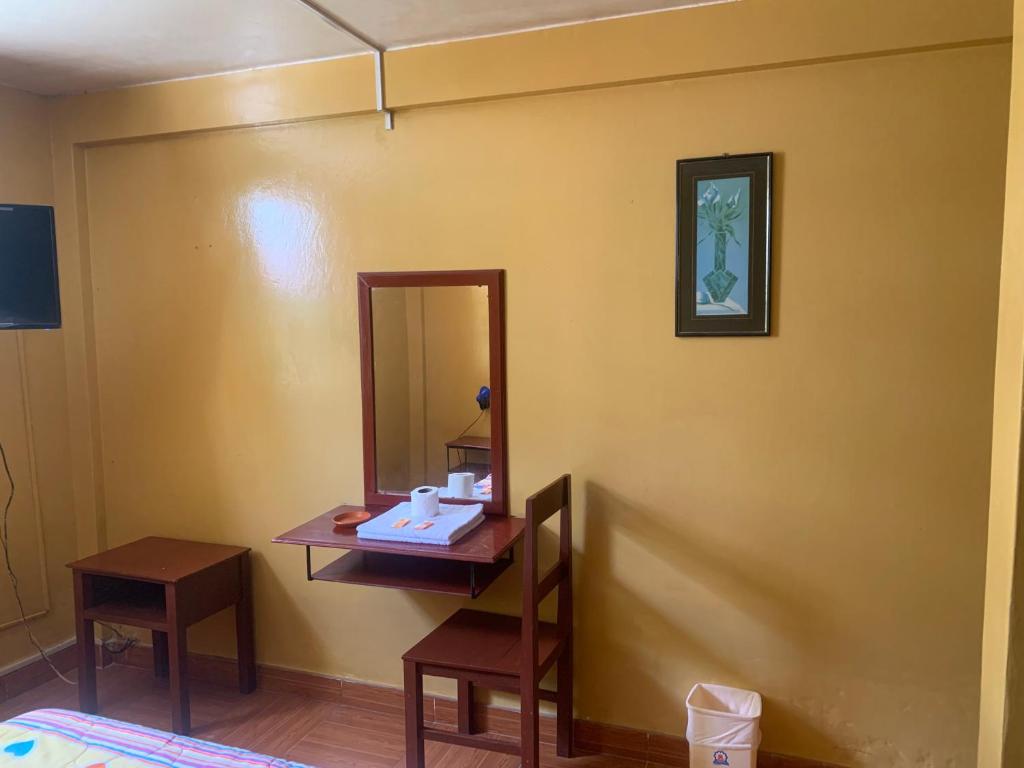 a bathroom with a vanity with a mirror and a table at Hostal Residencial La Esmeralda in Lima
