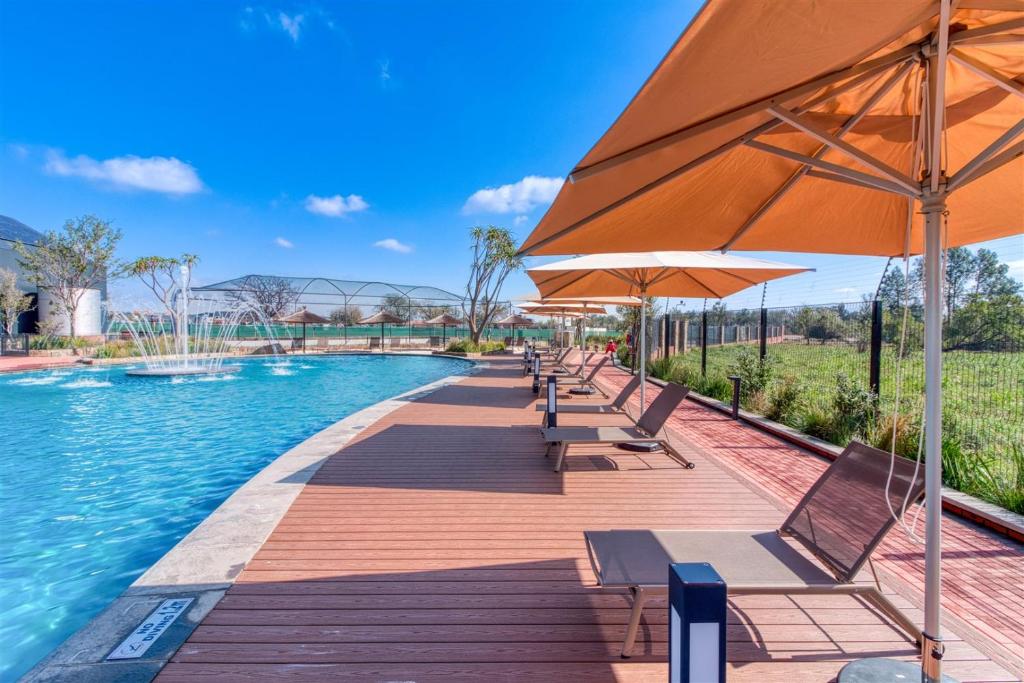 a swimming pool with chairs and an umbrella at The Lagoon Exquisite Apartments in Pretoria