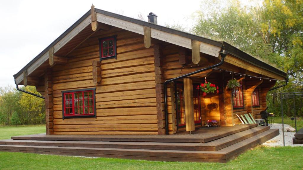 Cabaña de madera con porche y ventanas rojas en Koidu Puhkemaja, en Suurevalja