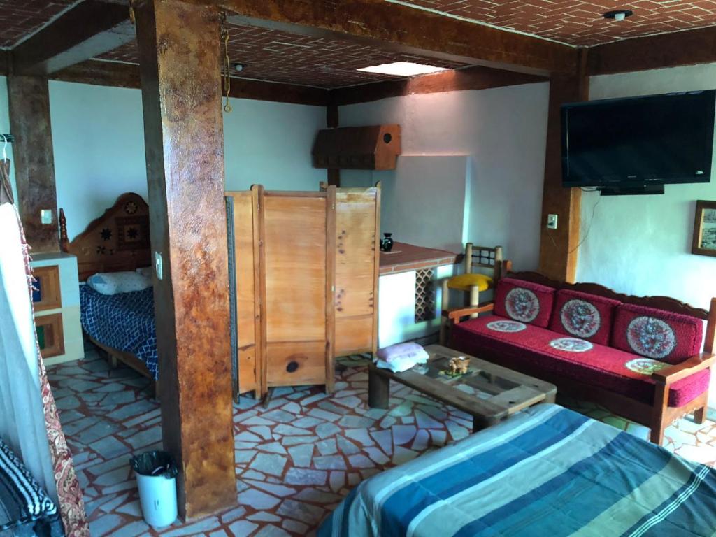 a room with a bed and a couch and a tv at Luna in Taxco de Alarcón