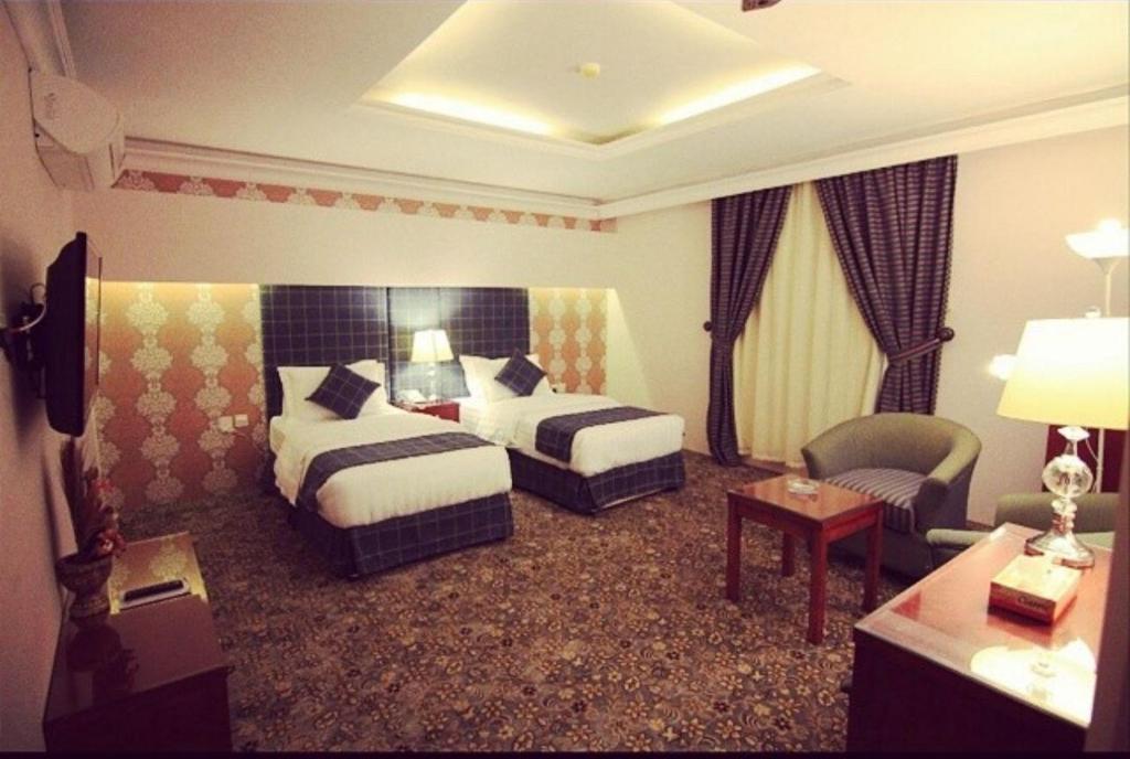 a hotel room with two beds and a chair at بنان فال للشقق المخدومة in Hafr Al Baten