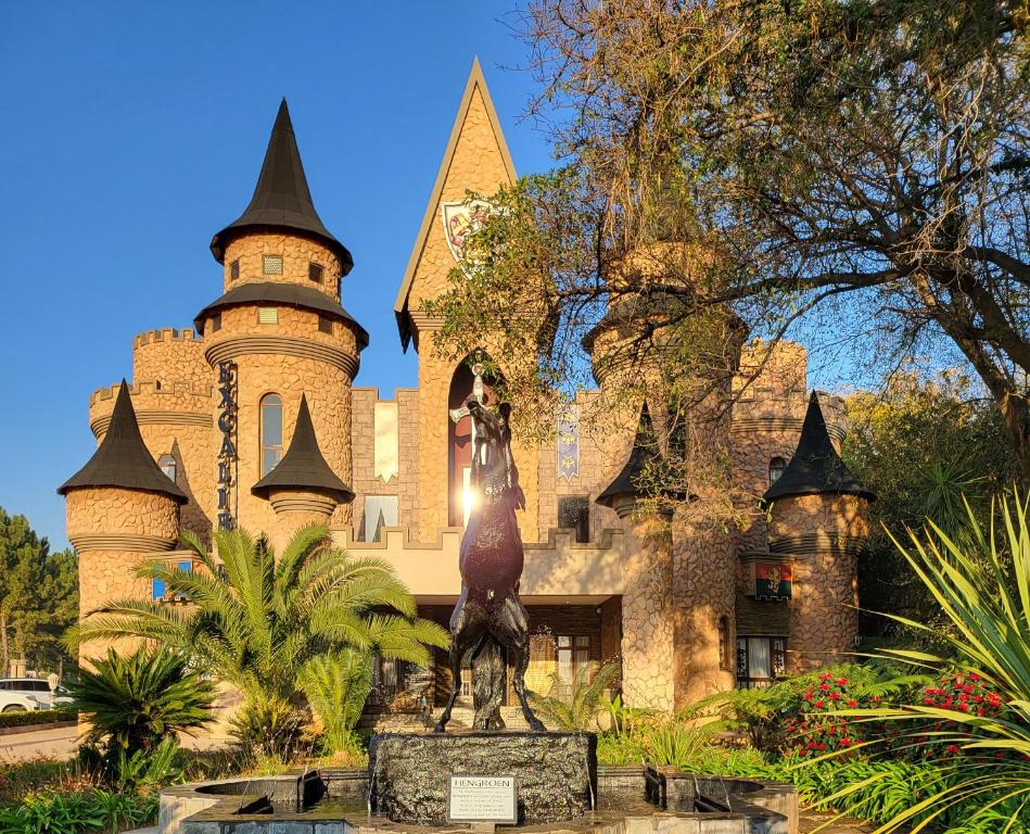 a castle with a statue in front of it at Excalibur Boutique Hotel in Rustenburg