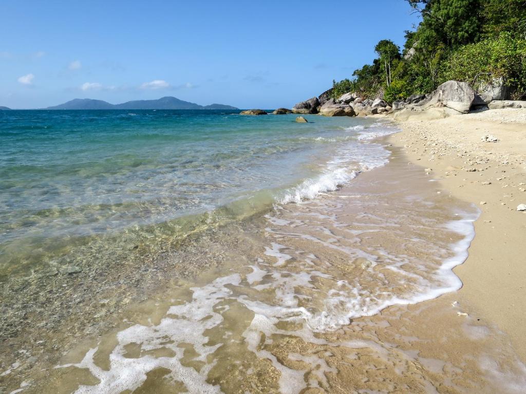 a sandy beach with the ocean and mountains in the background at Mission Beach Hideaway Holiday Village in Mission Beach