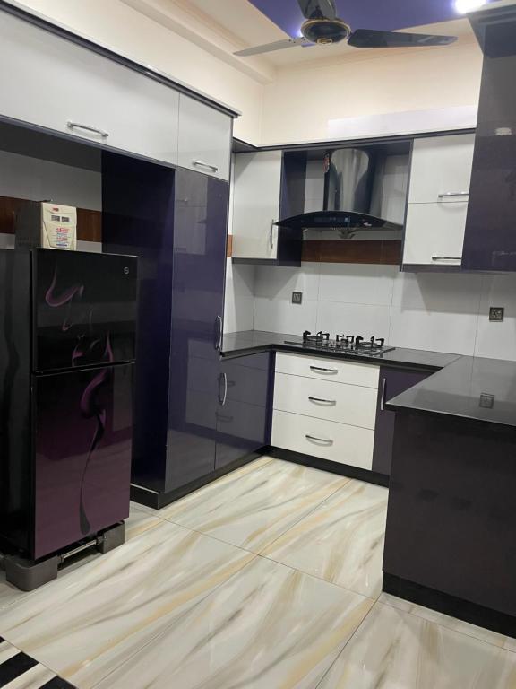 Il comprend une cuisine équipée d'un réfrigérateur noir et de placards blancs. dans l'établissement BAHRIA PRIVATE HOME, à Rawalpindi